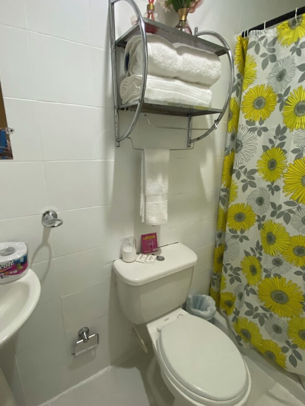 Un baño con inodoro, lavamanos y cortina de ducha.