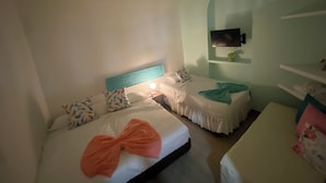 Habitación de hotel con dos camas, un televisor montado en la pared y una mesita de noche con lámpara.