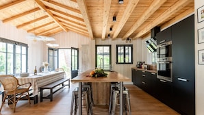Una cocina moderna con vigas de madera, una isla central, taburetes de bar y muebles negros.