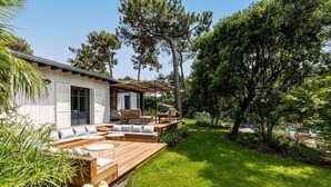 Una casa moderna con terraza de madera, mobiliario exterior y piscina.
