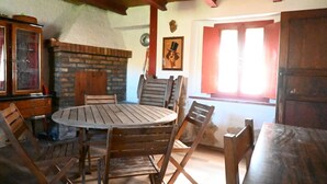 Un comedor rústico con una mesa redonda de madera y sillas, una chimenea de ladrillo y un mueble de madera.