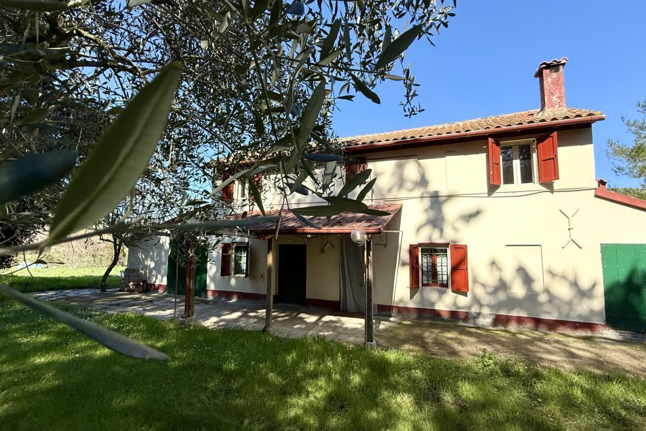 Una casa de dos pisos con techo de tejas rojas, un porche cubierto y una puerta verde.