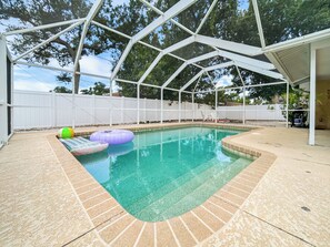 Una piscina con techo blanco, rodeada por una cerca blanca y agua azul cristalina.