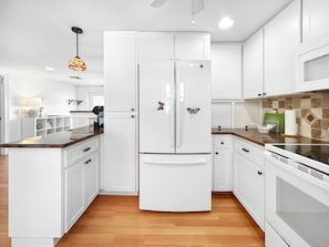 Una cocina moderna con armarios blancos, una isla central y un horno empotrado.