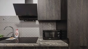 A modern kitchen with a black microwave, a sink with a faucet, and a bottle of Fairy dishwashing liquid. - Winogrady Nature Escape Apartment (Poznań)