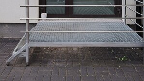 A modern building entrance with a metal staircase leading to a door with a glass panel. - Winogrady Nature Escape Apartment (Poznań)