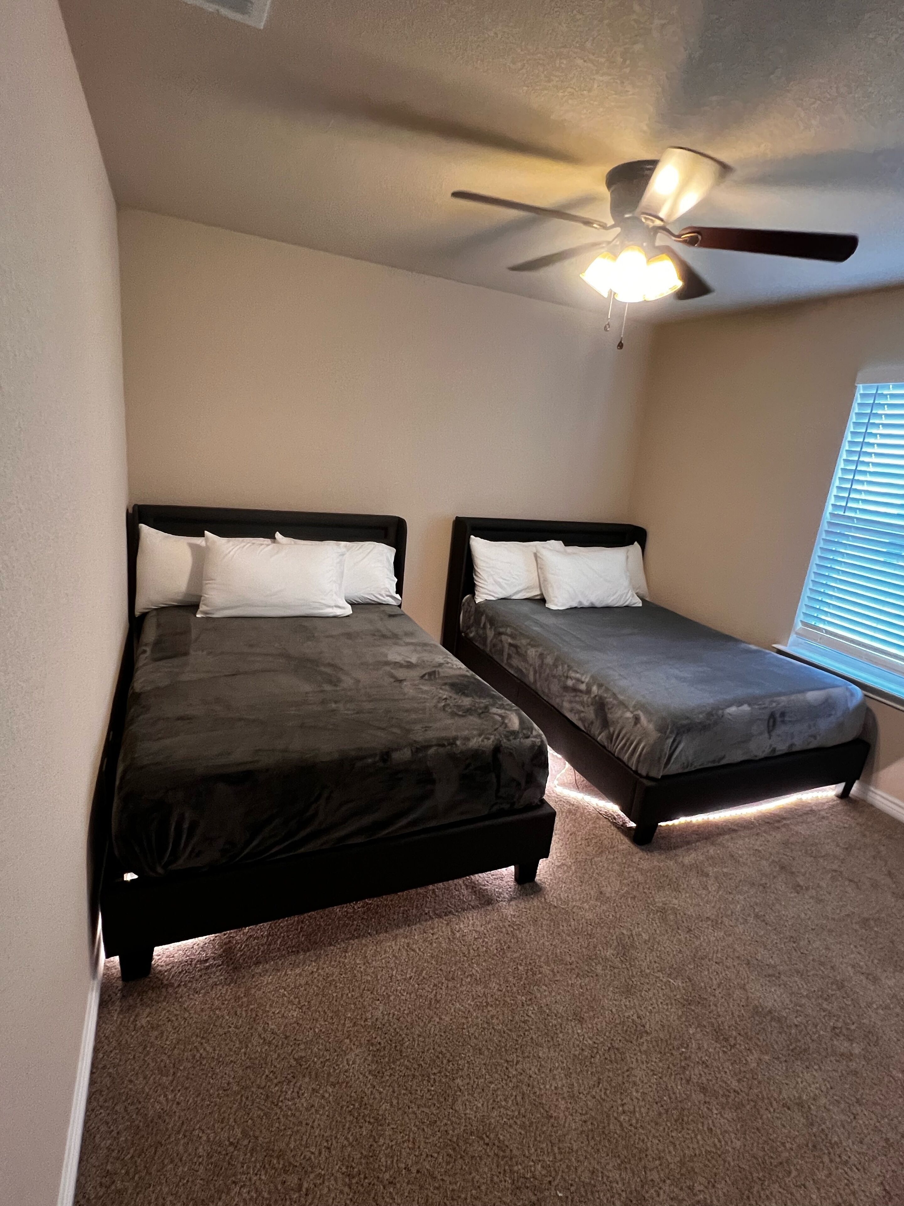 Ein Schlafzimmer mit zwei Einzelbetten, einem Deckenventilator und einem Fenster mit Jalousien.