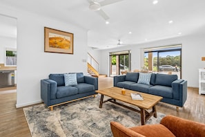 A modern living room with two sofas, a coffee table, and a rug. - Currimundi Lake House Pet Friendly (Currimundi)