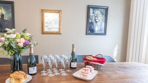 A dining table with a bottle of champagne, multiple wine glasses, a plate of pastries, and a basket of bread.