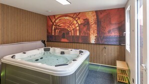 A modern bathroom with a large bathtub, wooden paneling, and a large mural on the wall.