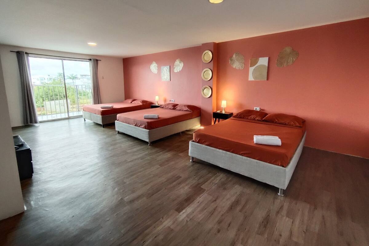 A hotel room with two beds, a large window, and a balcony.