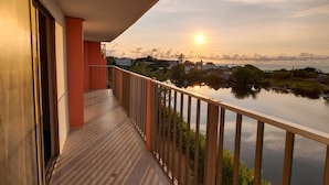 Un balcon donnant sur une étendue d’eau et sur un coucher de soleil.