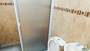 Une salle de bain comprenant des toilettes, un lavabo et un espace douche.