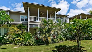 A two-story building with a covered porch and a lawn with tropical plants. - Bright & Spacious 2br/2ba Villa-Ko'Olina Resort (Kapolei)