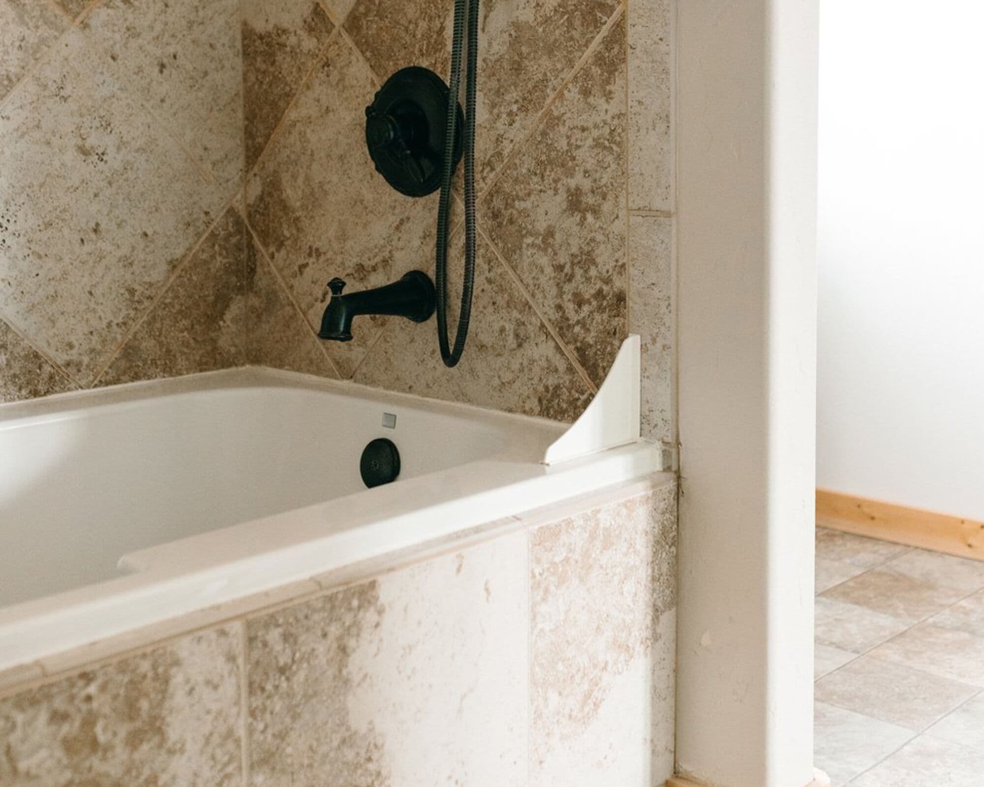 Una bañera con ducha de mano y grifo.