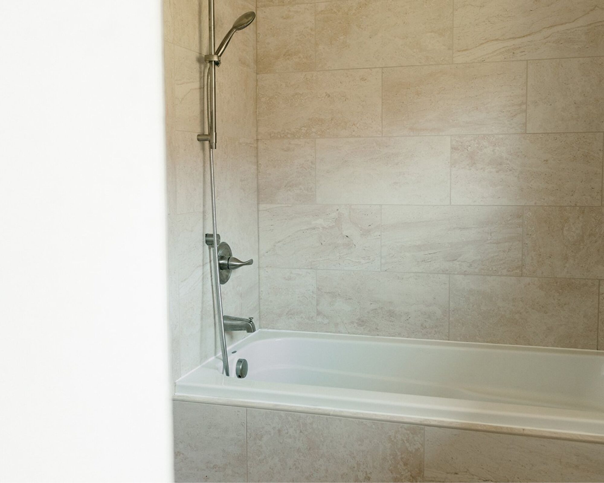 A bathroom with a bathtub, a showerhead, and a handheld shower.