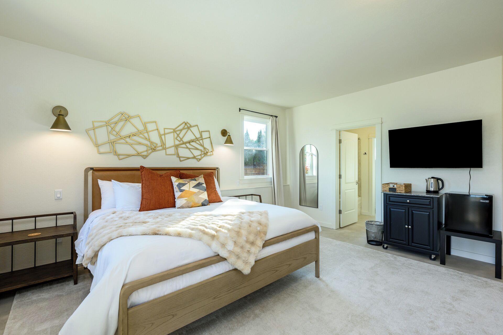 A bedroom with a bed, bedside tables, a TV, and a window.