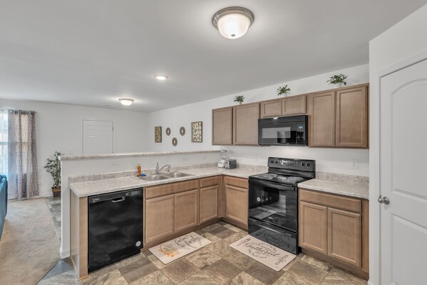 A modern kitchen with wooden cabinets, a dishwasher, a stove, and a microwave.