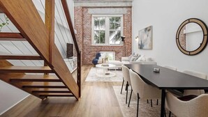 A modern interior with a staircase, a dining area, and a brick wall. - Woolstore Style! ~ 2Bed/2Bath/1Car ~ Teneriffe (Teneriffe)