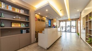 A reception area with a reception desk, shelves with various items, and a large window in the background. - Shanghai Yaya Light Luxury Hotel (Hongkou Football Stadium) (Shanghai)