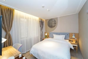 A hotel room with a bed, bedside tables, a desk, and a chair.