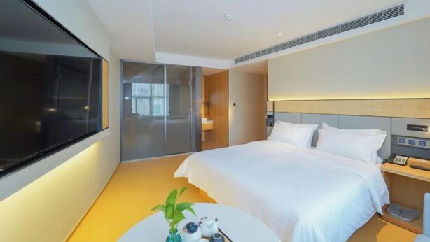 A modern hotel room with a large bed, bedside table, and a view of the city. - Shanghai Yaya Light Luxury Hotel (Hongkou Football Stadium) (Shanghai)