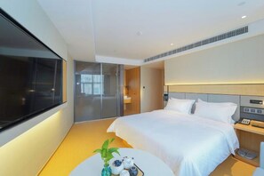 Une chambre d’hôtel moderne avec un grand lit, une table de chevet et une vue sur la ville.