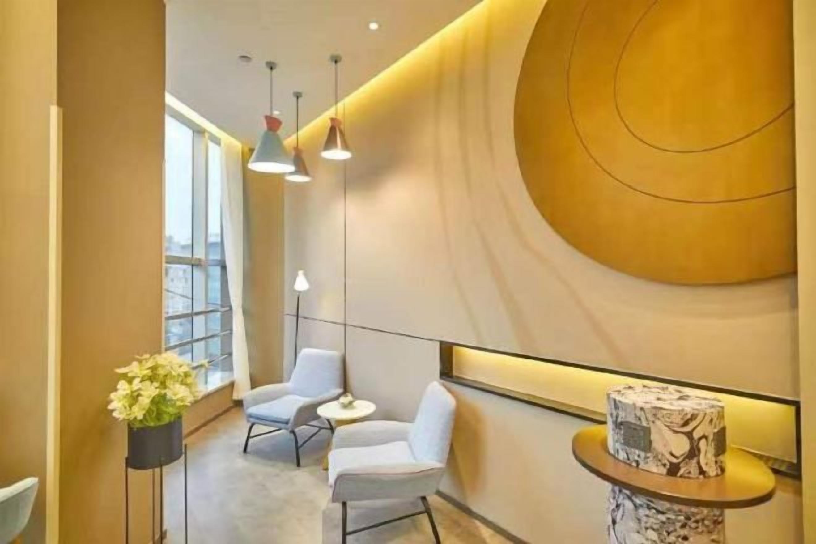 Un interior moderno con una pared curva, dos zonas de estar, iluminación colgante y un ventanal grande.
