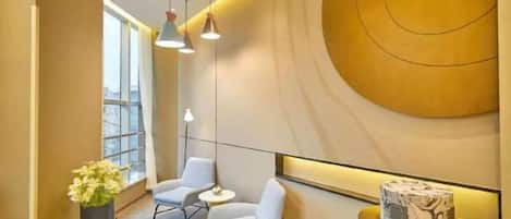 Un interior moderno con una pared curva, dos zonas de estar, iluminación colgante y un ventanal grande.