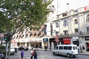 A street scene with a white van, pedestrians, and buildings with commercial signs. - Shanghai Yaya Light Luxury Hotel (Hongkou Football Stadium) (Shanghai)