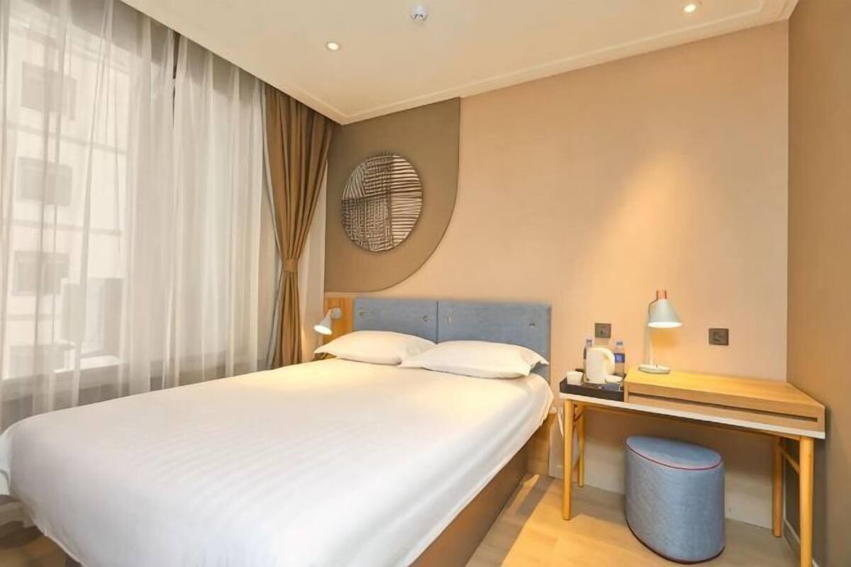 Ein Hotelzimmer mit Bett, Nachttisch, Lampe und einer runden Wanddekoration.