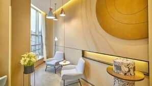 A modern interior with a curved wall, two seating areas, and a decorative column. - Shanghai Yaya Light Luxury Hotel (Hongkou Football Stadium) (Shanghai)