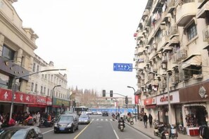 A street view with buildings, shops, and a clear sky. - Shanghai Yaya Light Luxury Hotel (Hongkou Football Stadium) (Shanghai)