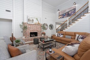 A modern living room with a brick fireplace, a sofa set, a coffee table, and a staircase. - Abilene Icon- Sky, Story, and the Western Spirit! (Abilene)