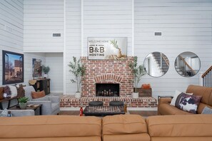 Ein modernes Wohnzimmer mit Kamin aus Ziegeln, einer Couch, einem Couchtisch und einem Schild mit der Aufschrift 'WELCOME HOME B&B HOSTING'.