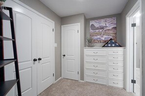 A hallway with white doors, a white dresser with drawers, and a framed picture on the wall. - Abilene Icon- Sky, Story, and the Western Spirit! (Abilene)