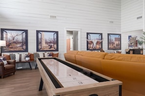 Una sala de estar con mesa de billar, sofá y obras de arte colgadas en la pared.