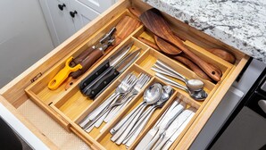 Un cajón con varios utensilios y herramientas de cocina, incluyendo cuchillos, cucharas y un ablandador de carne.