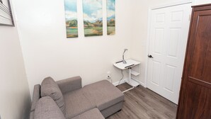 A room with a grey sectional sofa, a white door, and three landscape paintings on the wall. - Charming 3-bedroom apartment with AC, WiFi in lovely Jersey City (Jersey City)
