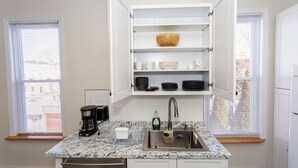 Una cocina con encimera de granito, pileta integrada, cafetera y escurreplatos.