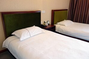 A hotel room with two single beds, each with a wooden headboard and white bedding. There is a nightstand with a clock and a phone between the beds. - Yongxiang Business Hotel (Shanghai)