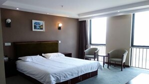 A hotel room with a large bed, a chair, a small table, and a balcony with curtains. - Yongxiang Business Hotel (Shanghai)