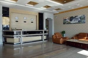 A modern lobby with a reception desk, leather seating, a coffee table, and a painting on the wall. - Yongxiang Business Hotel (Shanghai)