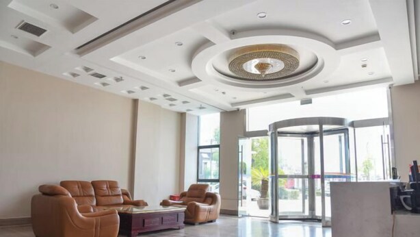 A spacious lobby with a modern ceiling design, a revolving door, and leather seating. - Yongxiang Business Hotel (Shanghai)