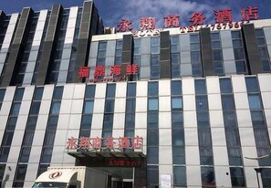 Een hotel met meerdere verdiepingen, grote ramen en een opvallend bord met contactgegevens.