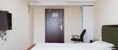 A hotel room with two beds, a desk, a chair, and a television mounted on the wall.