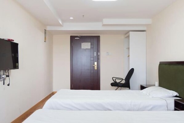 A hotel room with two beds, a desk, a chair, and a television mounted on the wall. - Yongxiang Business Hotel (Shanghai)