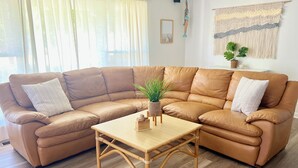Una sala moderna con un sofá seccional de cuero marrón, una mesa de centro de madera y una planta en maceta.