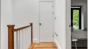 A hallway with wooden flooring, white walls, and a skylight. - Spacious Modern House 3BR 3BA Balcony Park View (London)