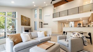 Un amplio espacio de sala con sofá, reposapiés y una mesa de comedor.
